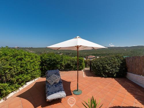 a chair and an umbrella on a brick patio at House Eleonora in Cala Sapone