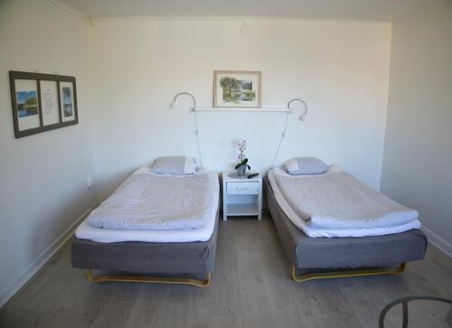 a room with two beds and a night stand in it at Bergåsa bed & kitchen Drängsered in Torup