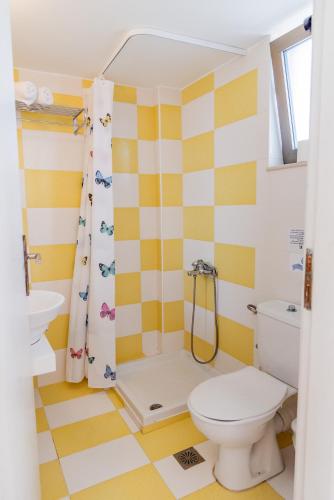 a yellow and white bathroom with a toilet and a shower at Almyra Apartments & Suites in Sfakaki