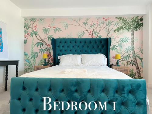 a bed with a blue headboard in a bedroom at Shan Mu Inn Deluxe Hot-tub seaview apartment in Newlyn