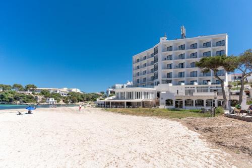 un edificio sulla spiaggia vicino a una spiaggia di Hotel Playa Santandria Adults Only a Cala Santandria