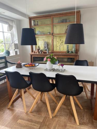 a dining room table with black chairs and two lamps at Cool familyhome 400 m. from the beach in Espergærde