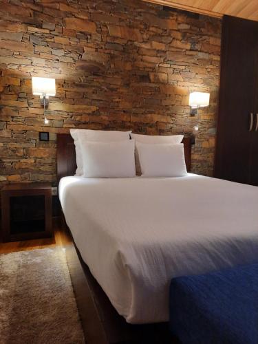 a large bed in a room with a brick wall at Casa da Eira de Cima in Chão Sobral