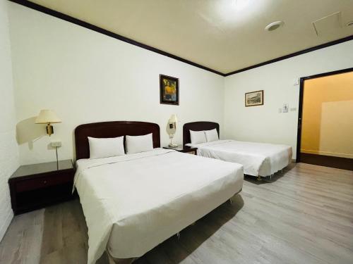 a hotel room with two beds and a mirror at Abbo Hotel in Tainan