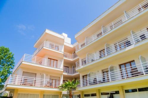 an apartment building with white balconies and palm trees at Hotel Hipica Park in Platja  d'Aro