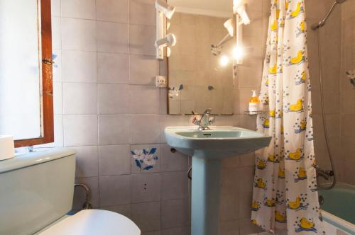 a bathroom with a sink and a toilet and a shower curtain at Pension Iberia in Llanes