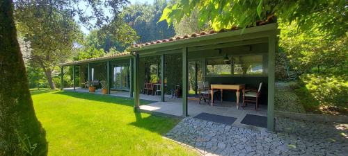 a green house with a table and chairs in a yard at Casas da Tapada Briteiros Casa dos Ficos in Guimarães