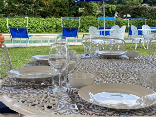 a table with plates and wine glasses on it at Villa con piscina tra Versilia e Cinque Terre in Luni