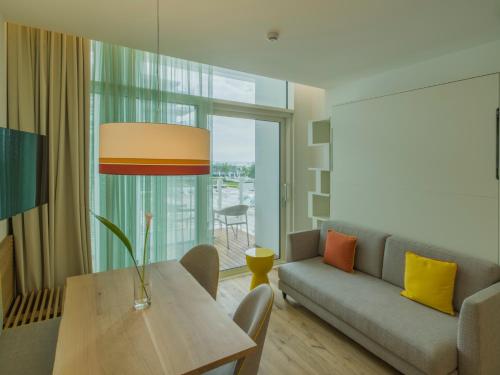 a living room with a couch and a table at Falkensteiner Residences Jesolo in Lido di Jesolo