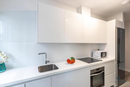 cocina con armarios blancos, fregadero y microondas en Living4Malaga Pacific Terrace Apartment, en Málaga