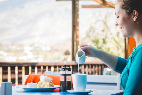 een vrouw aan een tafel met een kopje koffie bij Blue Cow Barn - Boutique Farm in Barrydale