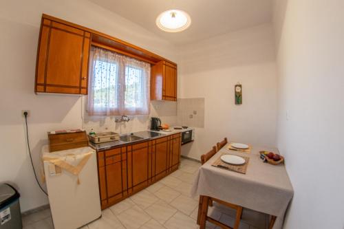 eine Küche mit Tisch, Spüle und Kühlschrank in der Unterkunft George Apartments in Arillas