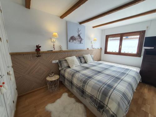 a bedroom with a bed with a plaid blanket at ES CÒVES in Vielha