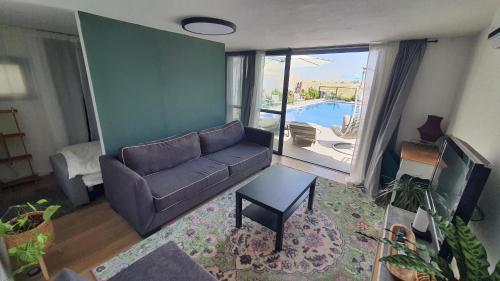 a living room with a couch and a view of a pool at צדפת המדבר in Giv'ot Bar