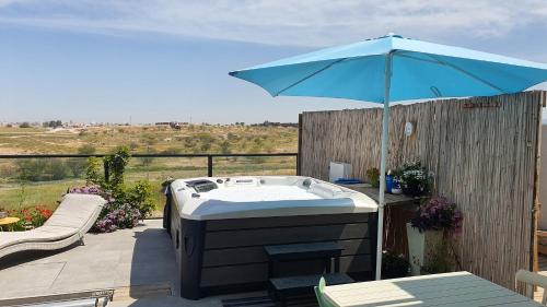 a hot tub with an umbrella on a patio at צדפת המדבר in Giv'ot Bar