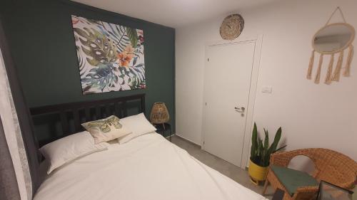 1 dormitorio con 1 cama y una pintura en la pared en צדפת המדבר, en Giv'ot Bar