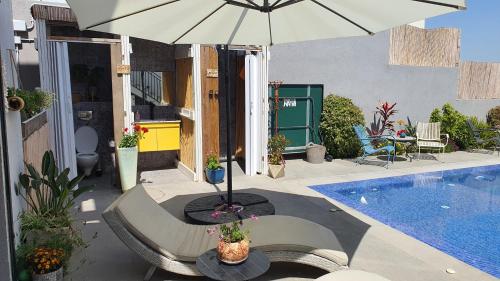 a patio with an umbrella next to a swimming pool at צדפת המדבר in Giv'ot Bar
