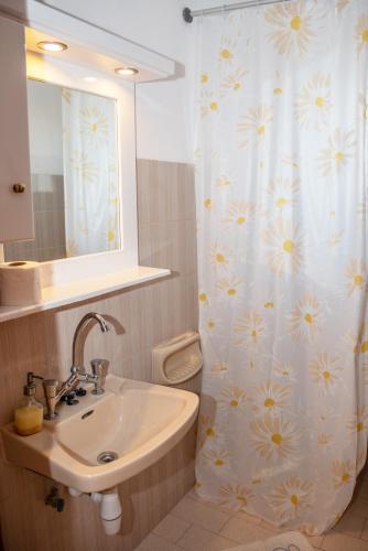 a bathroom with a sink and a shower curtain with flowers at George Apartments in Arillas