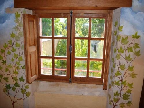 a window in a room with a mural of trees at Maison spacieuse à Saint-Martin-des-Entrées avec jardin in Saint-Martin-des-Entrées