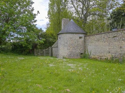 an old brick wall with a gate and a grass field at Maison spacieuse à Saint-Martin-des-Entrées avec jardin in Saint-Martin-des-Entrées