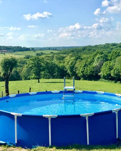 une grande piscine bleue au milieu d'un champ dans l'établissement gîte Aux Petits Bonheurs avec vue panoramique, à Perrigny-sur-Loire