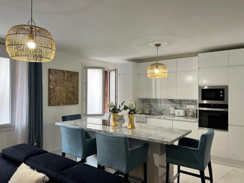 une cuisine avec une table avec des chaises bleues et deux lumières dans l'établissement Magnifique appartement proche plage Marseille 7, à Marseille