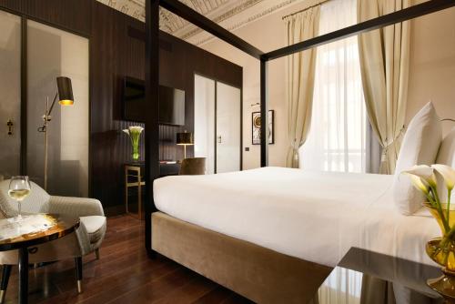 a hotel room with a large white bed and a table at Hotel L'Orologio Roma - WTB Hotels in Rome