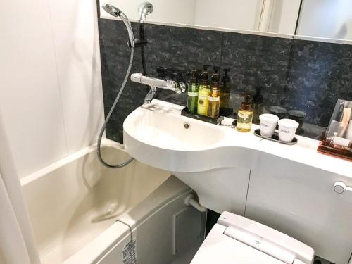 a bathroom with a sink and a toilet and a shower at HOTEL LiVEMAX Chiba Chuo-Ekimae in Chiba