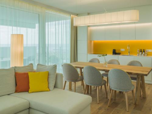 a living room with a couch and a table with chairs at Falkensteiner Residences Jesolo in Lido di Jesolo