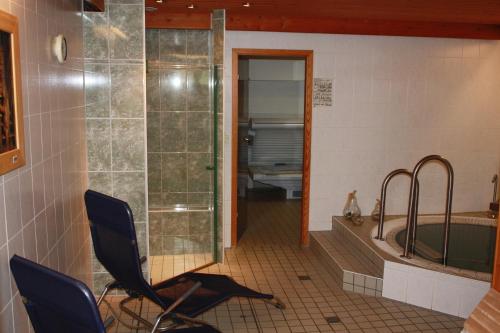a bathroom with a shower and a tub and a chair at Wellness Hotel Pension & Gaststätte Riedel in Kurort Oberwiesenthal