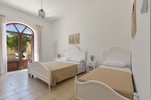 two beds in a white room with a window at Villa La Paiara by Perle di Puglia in Borgagne