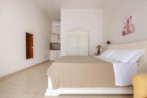 a white bedroom with a large bed and a kitchen at Villa La Paiara by Perle di Puglia in Borgagne