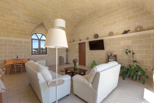 a living room with two white chairs and a table at Villa La Paiara by Perle di Puglia in Borgagne