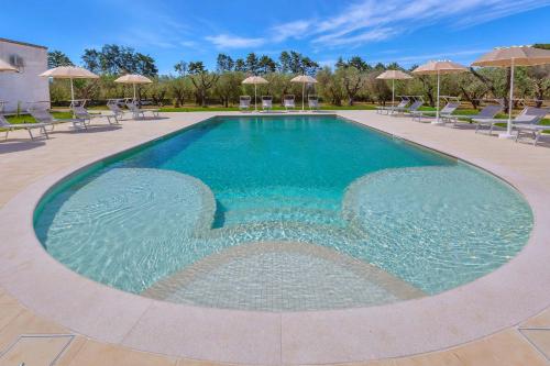 a large swimming pool with chairs and umbrellas at Villa La Paiara by Perle di Puglia in Borgagne