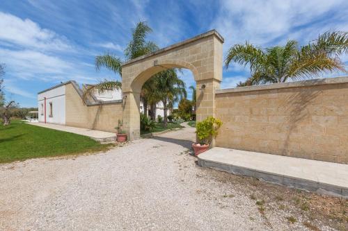 a brick wall with an arch in a yard at Villa La Paiara by Perle di Puglia in Borgagne