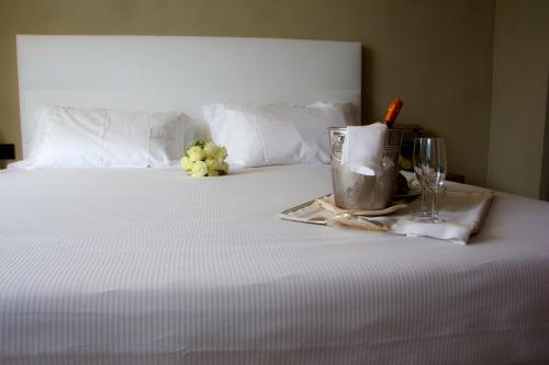 a white bed with a tray with a drink and wine glasses at Hotel San Rocco in Orta San Giulio