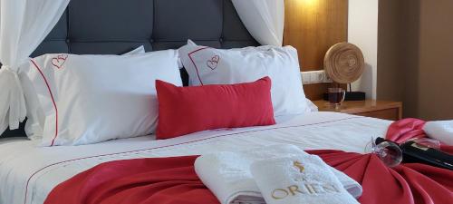 a bed with red and white pillows on it at Cavo Orient Beach Hotel & Suites in Tragaki