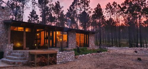 a stone house with a table in front of a forest at Krakeelpoort Herberg in Botrivier
