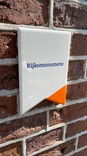 a white sign on a brick wall at PUUR Eastermar - monumentaal, authentiek en luxe koetshuis aan open vaarwater met jacuzzi en sauna in Oostermeer