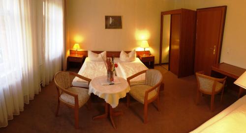 ポツダムにあるPension an der Havelbuchtのベッド、テーブル、椅子が備わるホテルルームです。