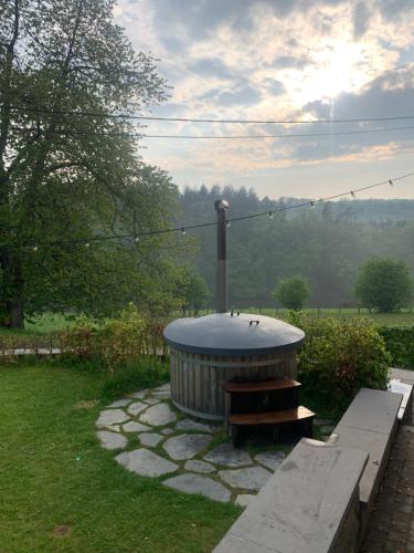 a fire pit with a bench in a yard at vakantiehuis met hottub en zicht op de Semois in Herbeumont
