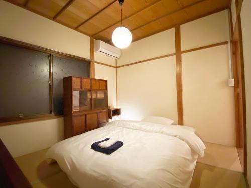 1 dormitorio con cama blanca y cinturón azul en 湊庵 赤橙 -so-an sekitou-, en Inatori