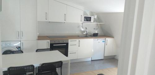 a kitchen with white cabinets and a table and chairs at APARTAMENTOS DON MANUEL B in Cee
