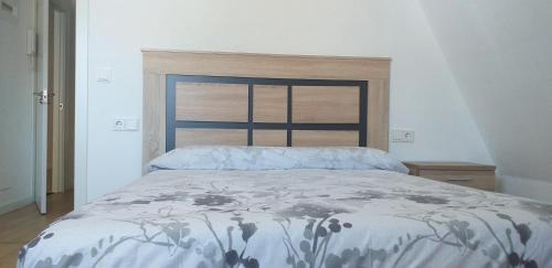 a bedroom with a bed with a blue and white comforter at APARTAMENTOS DON MANUEL B in Cee