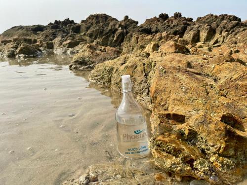 a bottle of mineral water sitting on the beach at PHOENIX MINH CHÂU HOTEL in Quang Ninh