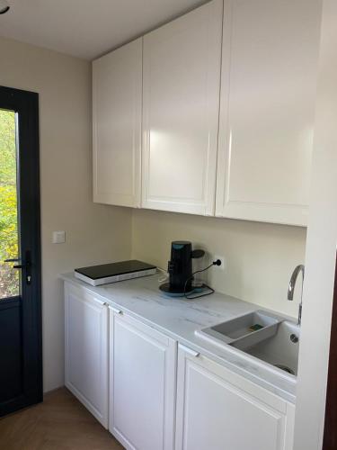 a white kitchen with white cabinets and a sink at Private room among a nice Garden - Jardin en valois in Magnac-sur-Touvre