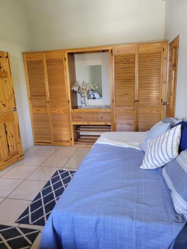 a bedroom with a blue bed and wooden cabinets at Memories Cottage and Apartments in Buccoo