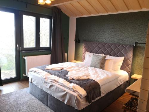 een slaapkamer met een groot bed in een kamer met ramen bij Wood Villa Mátra in Matraszentlaszlo