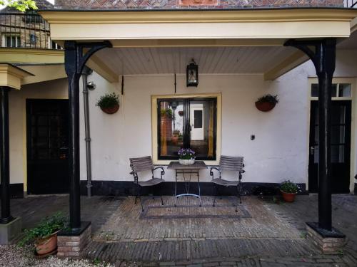 a porch with two chairs and a table in front of a house at Unique Courtyard House with Sauna in Alkmaar city center in Alkmaar