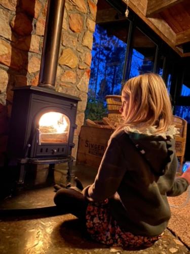a woman sitting on the floor in front of a fireplace at Krakeelpoort Herberg in Botrivier